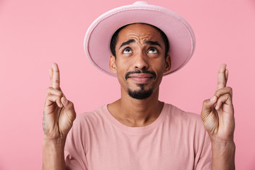 Photo of african american man looking upward with fingers crossed