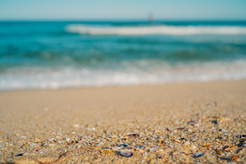 Fototapeta na wymiar Focus on the sandy beach and focused out gentle waves on a clear fine day with no cloud in the sky