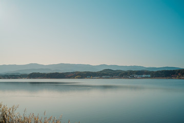 Calm surface of lake and long shot of layered mountains at Gangneung, South Korea