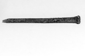 black and white image of a rusty nail covered with a brown oxidant on a white background