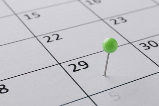 Planning calendar with green pin close up. Important date. Place for text. Planning concept.