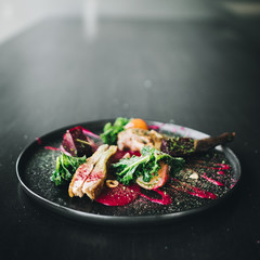 Michelin restaurant serving organic duck meat with kale and Beet puree on dark plate, chef cooking food