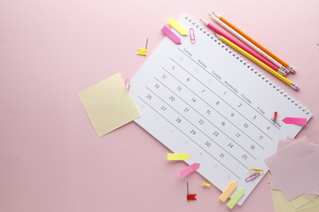Planning calendar on a pink background with pins, pencils, stickers .. Important date. Place for text. Planning concept.