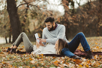  Young happy couple reading book together in autumn