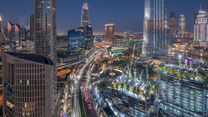 Naklejka na ściany i meble Panoramic skyline view of Dubai downtown after sunset with mall, fountains and skyscrapers aerial day to night timelapse