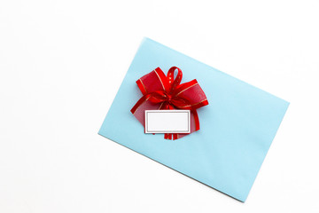 Blank paper blue envelope with red ribbon bow, letter for mail on white background, flat lay, top view. Concept postal service or greeting card