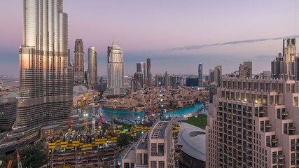 Fototapeta premium Panoramic skyline view of Dubai downtown after sunset with mall, fountains and skyscrapers aerial day to night timelapse