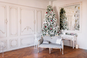 New Year 2020. Christmas beautiful lights on gold warm background. Christmas tree, toys. Photo of the interior of a room with a blue wall, garlands, fireplace with candles.