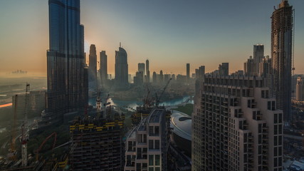 Panoramic skyline view of Dubai downtown during sunrise with mall, fountains and Burj Khalifa aerial morning timelapse