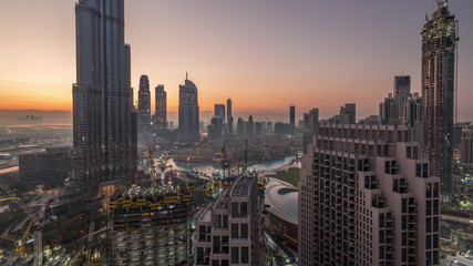 Fototapeta premium Panoramic skyline view of Dubai downtown before sunrise with mall, fountains and skyscrapers aerial night to day timelapse