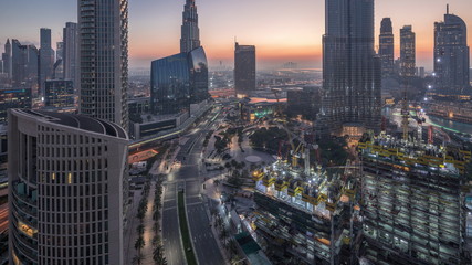 Fototapeta premium Panoramiczny widok na centrum Dubaju przed wschodem słońca z centrum handlowym, fontannami i drapaczami chmur z lotu ptaka z nocy na dzień timelapse