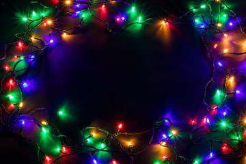 Christmas background with lights and free text space. Christmas lights border. Glowing colorful Christmas lights on black background. New Year. Christmas. Decor. Garland.