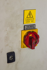 400V  AC electricity switch bright red and yellow on industrial machine. Huge button key lock for health and safety covered in dirt and grime.