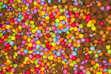 Fototapeta na wymiar An endless montage of colourful smarties both covered in sweets candy coating and uncoated straight chocolate sweets. Pink, purple, green, blue, yellow lovely background but unhealthy.