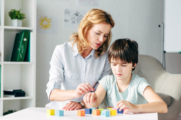 child psychologist and kid with dyslexia playing with building blocks