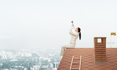 Beautiful young woman playing trumpet on roof