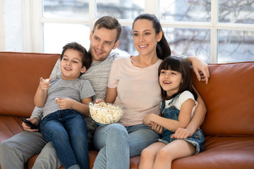 Happy family with kids enjoy movie eating popcorn