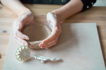 Woman making pottery, hands closeup, blurred background, focus on potters, palms with pottery. Turning passion into a job