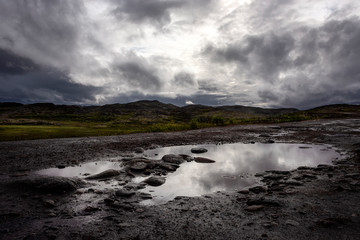 Russia, Arctic, Kola Peninsula, Barents Sea, Teriberka: Rural remote natural place with rocky wildness, dark grey gloomy cloudy sky and calm puddle water - concept outdoor adventure recreation nature