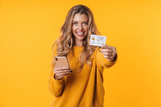 Image of charming blonde woman holding credit card and cellphone
