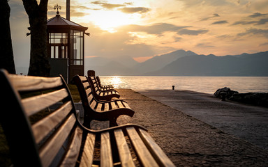 Lake Garda, Italy. A tranquil sunset view of benches looking over Lake Garda, Italy, towards the Italian Alps.