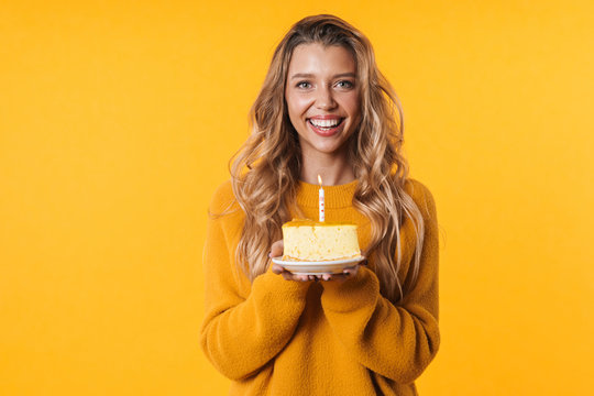 Image of joyful woman smiling and holding birthday cake with candle
