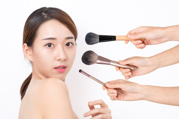 Portrait of beautiful woman with make-up brushes on white background