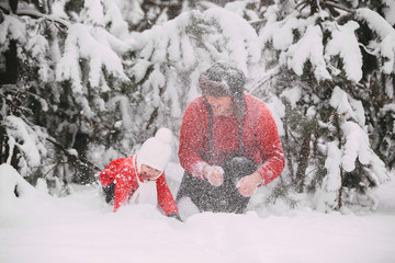 Portrait of happy little girl in red coat with dad having fun with snow in winter forest. girl playing with dad.