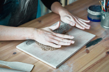 Woman making pattern on ceramic plate, hands close-up, focus on palms with clay and lace. Creative hobby concept, side hustle, turning hobbies into cash, passion into job