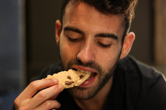 Young man with nose piercing eating chocolate cookie