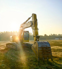 Yellow excavator at construction site into mud with sky background
