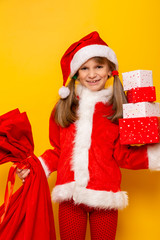Little girl dressed as Santa carrying Christmas presents