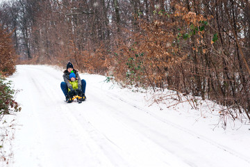 Happy family vacation in winter. Snowy weather. Little boy and mom enjoying winter. Happy family are sledging
