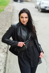 Stylish girl posing in street in fashionable outfit. Woman in black leather jacket and small...