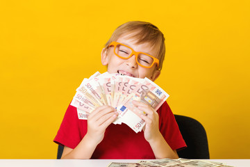 Excited boy in glasses with a fan of money. Future savings. Financial literacy of children. Kid thinking where to invest money