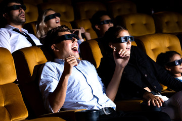Movie in cinema theatre for entertainment and enjoyment concept. Picture of happy friends excited sitting watch movie on film in cinema eating popcorn and drinking water.