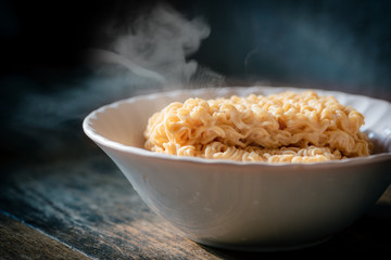 The smoke was poured from the boiled instant yellow noodles that had been boiled in hot water and brought out from a boiling pot in a bowl to be prepared as a food menu.