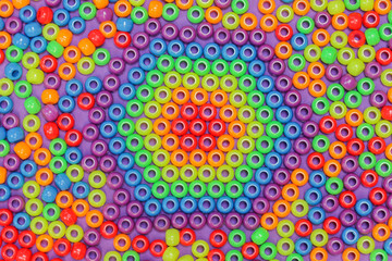 Close up multicolured plastic necklace beads of red, orange, yellow, green blue and purple