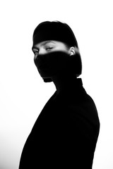 Fashionable beauty portrait. Black silhouette on white background. Girl with a spot of light on her face. 