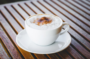 close up modern hot black coffee the cappuccino on wood background with coffee bubble foam pattern and texture in white cup looking and feel so delicious on glasses table in coffee shop.