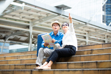 Senior couple traveling with luggage checking city map and sightseeing Travel and tourism concept.