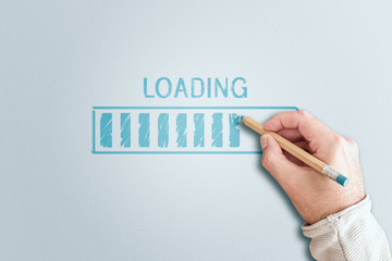 directly above shot of hand holding pencil drawing progress bar with word LOADING