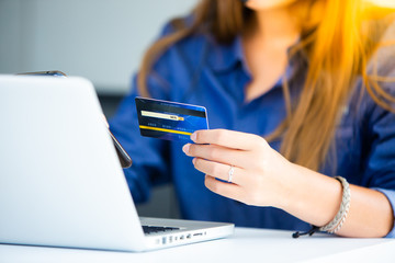 online shopping concepts. Woman hand  holding mobile phone and credit card with Payment Detail page display. using smartphone and laptop computer for online shopping