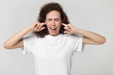 Stressed millennial girl cover ears avoiding noise