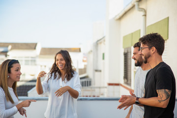 Fototapeta premium Happy excited friends playing game on terrace. Young men and women in casual meeting outside. Leisure time together concept