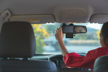 Portrait of woman in the car adjusts the rear view mirror before travel. Safety concept.