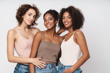 Portrait of three seductive multiethnic women standing together and smiling