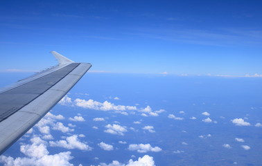 Fototapeta premium Airplane wing on the blue sky and clouds, View from window of plane.
