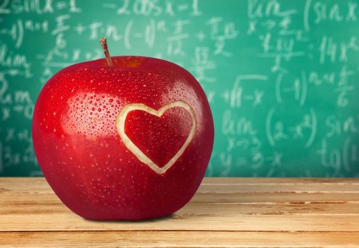 Photo of red apple with heart on the school desk