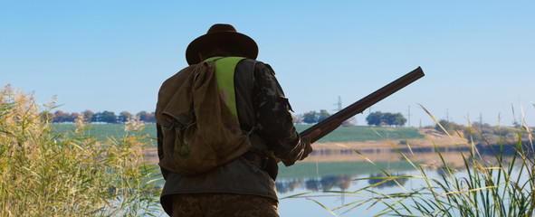 Hunting period, autumn season open. A hunter with a gun in his hands in hunting clothes in the...